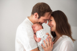 Babyfoto neugeborenes Baby schmust mit Mutter und Vater