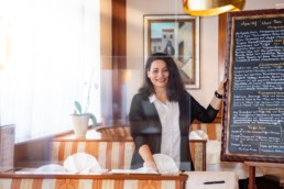 Luana Basoni in ihrem Restaurant Costa Smeralda mit der Speisekarte auf einer Tafel - Fotoprojekt Nur-so-halb von Stefanie Morlok Fotografin